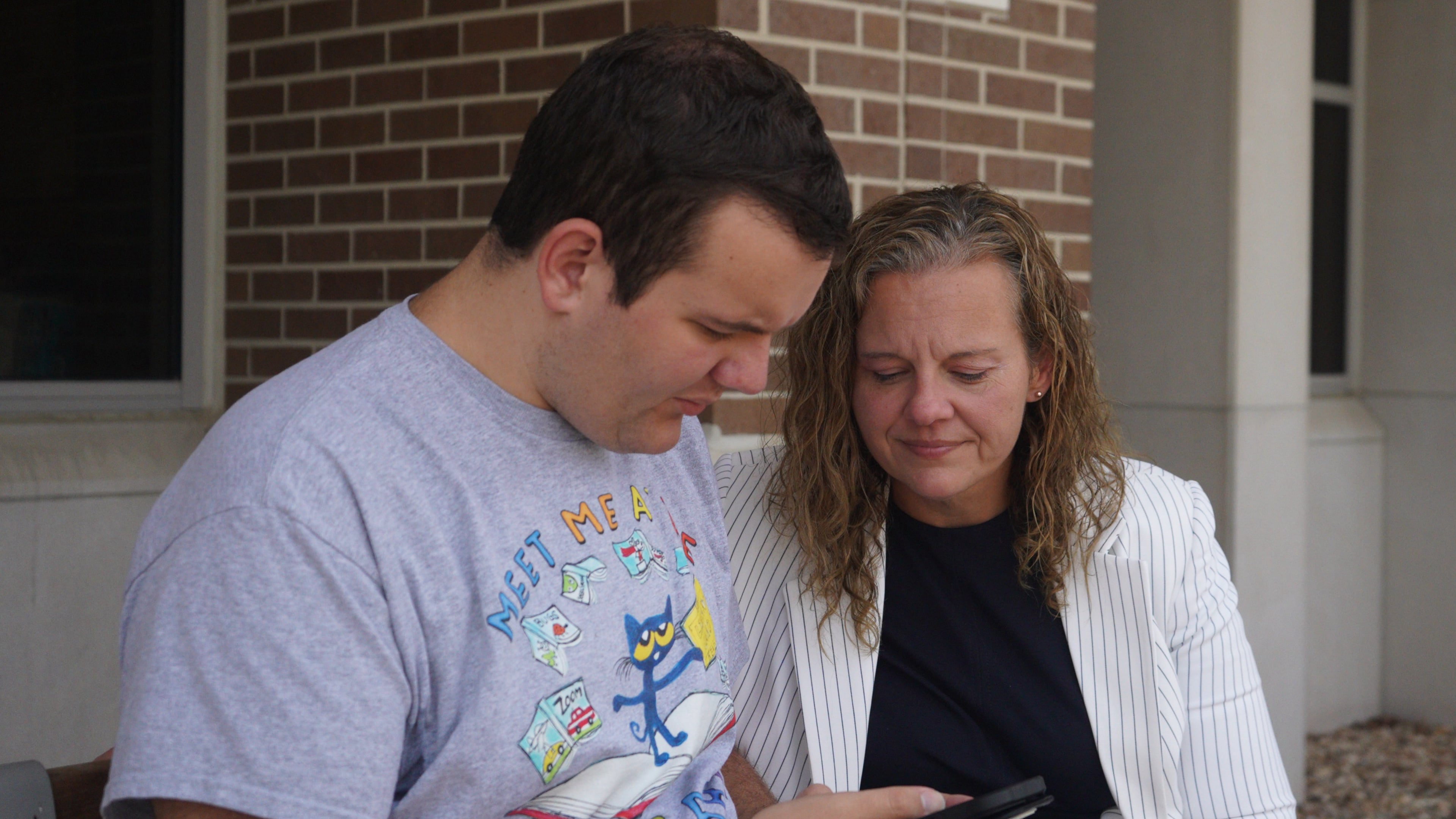 Rachel Deaton, director of training and legislation at the Autism Society of Indiana, sits with her 22-year-old autistic son, Luke, outside a public library in a northeastern suburb of Indianapolis, on Tuesday, Sept. 23, 2025. (AP Photo/Obed Lamy)