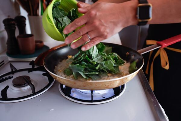 Add the collard greens, wine, and sesame oil and cook for another minute, or until the greens are wilted. Season with salt and white pepper and serve immediately. (Natrice Miller/AJC)