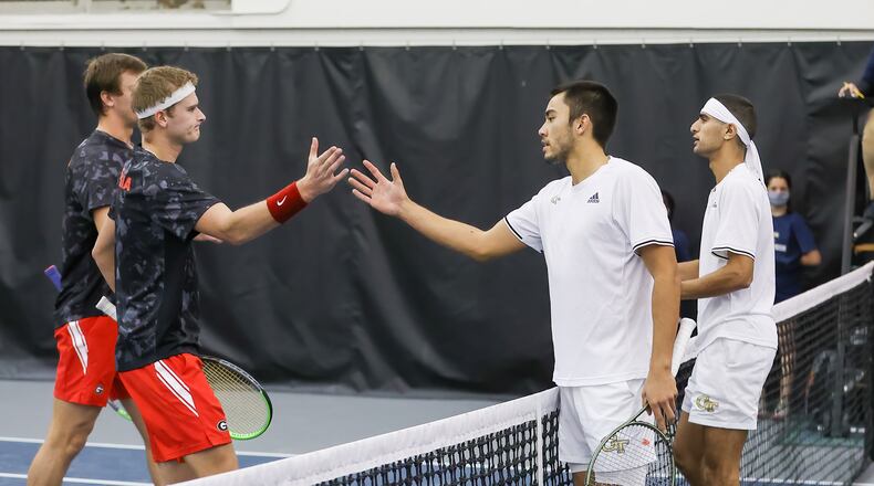 Georgia Tech's Marcus McDaniel (in white, extending his right hand) and Keshav Chopra (headband) congratulate Georgia's Tristan McCormick (obscured) and Hamish Stewart (in headband) in the Tech-Georgia tennis match Sunday at the Ken Byers Tennis Complex. McCormick and Stewart won the doubles match 6-3. The Bulldogs won the team match 4-3. (Ben Ennis/Georgia Tech Athletics)