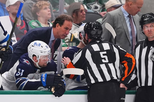 Winnipeg Jets head coach Scott Arniel, left, talks with referee Chris Rooney (5) in the third period of Game 3 of a second-round NHL hockey playoff series against the Dallas Stars in Dallas, Sunday, May 11, 2025. (AP Photo/Julio Cortez)