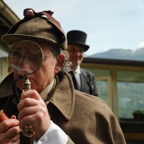 Philip Porter, playing Sherlock Holmes, looking through a magnifying glass during an event recreating the fateful confrontation between Sherlock Holmes and Professor Moriarty by the members of the Sherlock Holmes Society of London, at the Reichenbach Falls, Switzerland, May 3, 2026. (AP Photo/Niccolo Lupone, Pool)