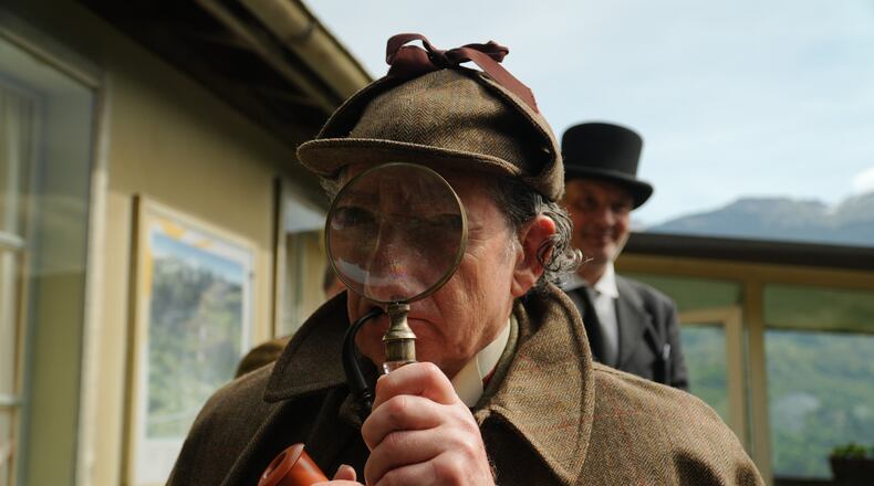 Philip Porter, playing Sherlock Holmes, looking through a magnifying glass during an event recreating the fateful confrontation between Sherlock Holmes and Professor Moriarty by the members of the Sherlock Holmes Society of London, at the Reichenbach Falls, Switzerland, May 3, 2026. (AP Photo/Niccolo Lupone, Pool)