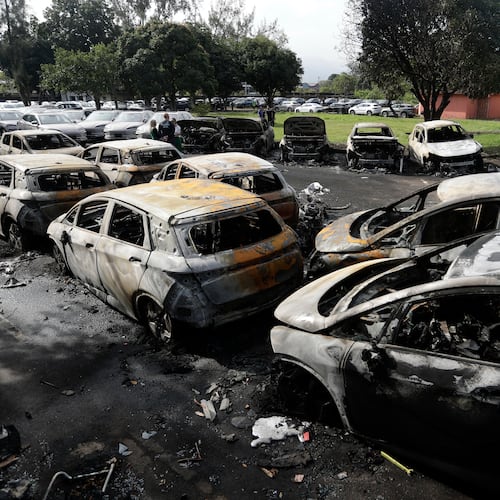 Burned vehicles fill a car dealership parking lot where, according to police, two helicopters collided in midair and crashed in Rio de Janeiro, Brazil, Sunday, June 14, 2026. (AP Photo/Bruna Prado)