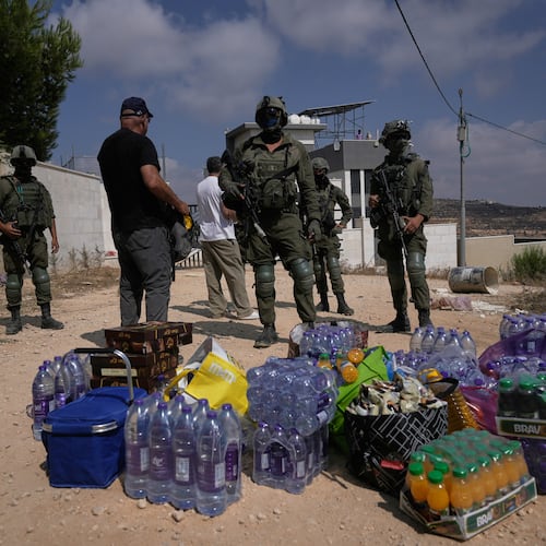 Activists accumulate food and water supplies in front of Israeli army soldiers who are blocking the road leading to the houses of three Palestinian families that have been besieged by Israeli settlers for six days, in the occupied West Bank village of Qusra, south of Nablus, Friday, Aug. 14, 2026. (AP Photo/Majdi Mohammed)