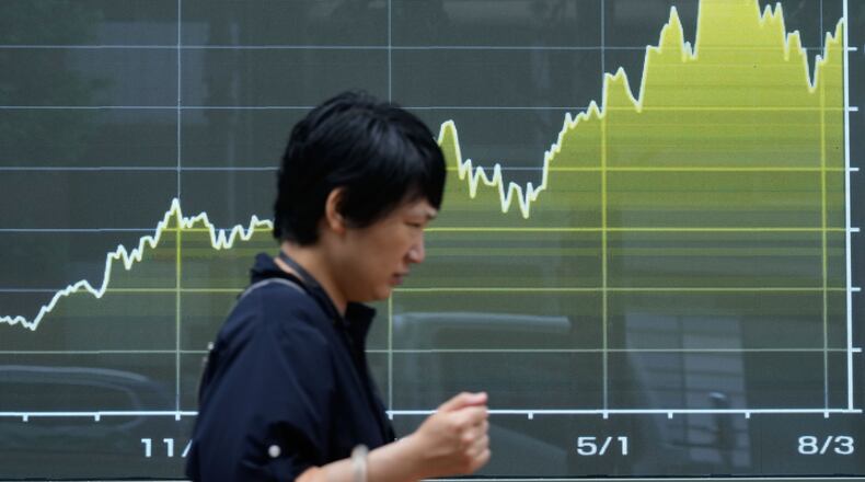 A person walk in front of an electronic stock chart board showing Japan's Nikkei index at a securities firm Thursday, Aug. 13, 2026, in Tokyo. (AP Photo/Eugene Hoshiko)