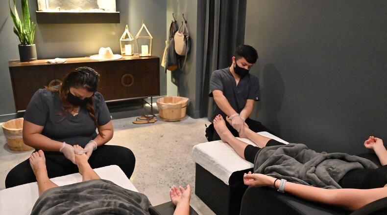 Viviana Torres (left) and Daniel Merida wearing mask and latex glove give customers a massage at Utopia Foot & Shoulder Massage in Atlanta on Thursday, June 11, 2020. PHOTO: Hyosub Shin / Hyosub.Shin@ajc.com