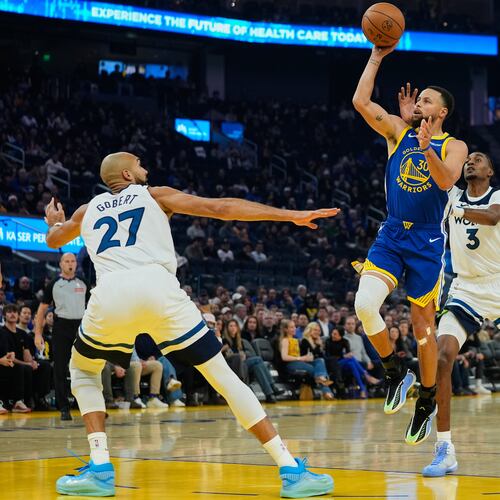 Golden State Warriors guard Stephen Curry (30) shoots between Minnesota Timberwolves center Rudy Gobert (27) and forward Jaden McDaniels (3) during the first half of an NBA basketball game, Friday, Dec. 12, 2025, in San Francisco. (AP Photo/Godofredo A. Vásquez)
