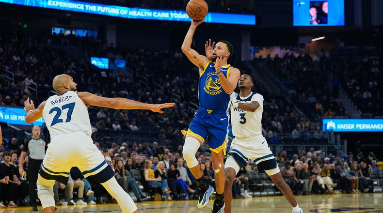 Golden State Warriors guard Stephen Curry (30) shoots between Minnesota Timberwolves center Rudy Gobert (27) and forward Jaden McDaniels (3) during the first half of an NBA basketball game, Friday, Dec. 12, 2025, in San Francisco. (AP Photo/Godofredo A. Vásquez)