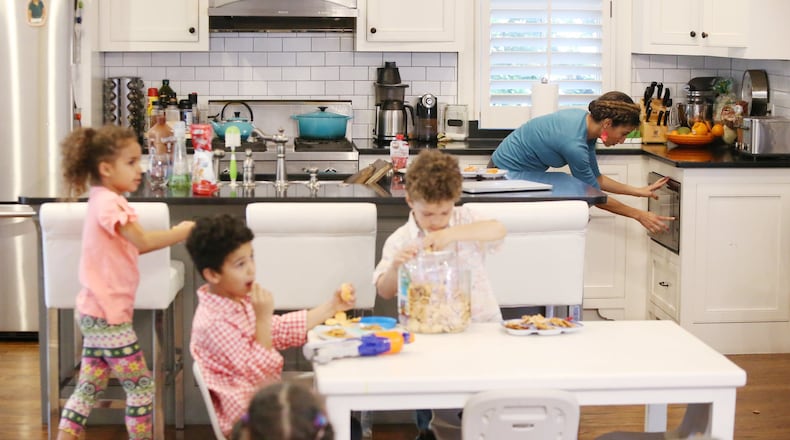 Debra Shigley, who has five children, heats up food for her youngest child while her other children enjoy a snack and a movie in their Atlanta home after playing outside. EMILY HANEY / EMILY.HANEY@AJC.COM