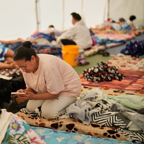 A woman checks her mobile phone at a temporary shelter for people whose homes were damaged after an earthquake struck Pereira, Colombia, Wednesday, Aug. 12, 2026. (AP Photo/Fernando Vergara)