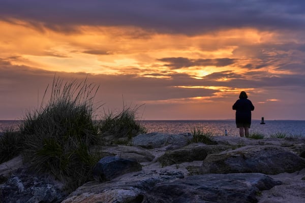 A woman views the sunset at Menemsha Beach, Wednesday, May 14, 2025, in Chilmark, Mass. (AP Photo/Robert F. Bukaty)