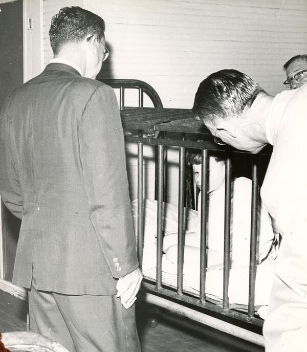 Visitors to Milledgeville State Hospital observe a small boy restrained in a metal cage in the 1940s. The facility, now known as Central State Hospital, currently operates only a unit for criminal defendants who are mentally ill. (AJC file)