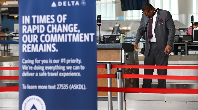 A Delta ticket agent cleans his work station while waiting for passengers in Atlanta Hartsfield-Jackson’s international terminal on Monday, March 30, 2020, in Atlanta. Curtis Compton ccompton@ajc.com