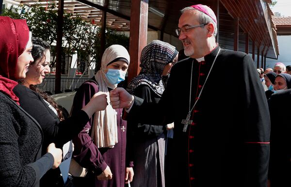 FILE - Latin Patriarch of Jerusalem Pierbattista Pizzaballa fist bumps as he is greeted on arrival to the Rosary Sisters School, which was damaged last month during an 11-day war between Israel and the Hamas militant group that rules Gaza, in Gaza City, Monday, June 14, 2021. (AP Photo/Adel Hana, File)