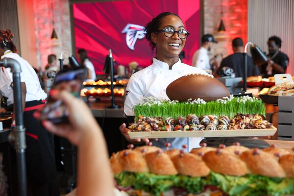 Executive sous chef Cat Turner holds a chocolate football during a media event showcasing new food and beverage options at Mercedes-Benz Stadium. (Arvin Temkar/AJC)