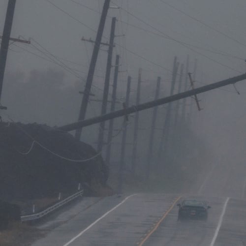 A vehicle drives near a downed utility pole dangling above Mamalahoa Highway during Hurricane Lala near Ocean View, Hawaii, Saturday, Aug. 15, 2026. (Stephen Lam/San Francisco Chronicle via AP)