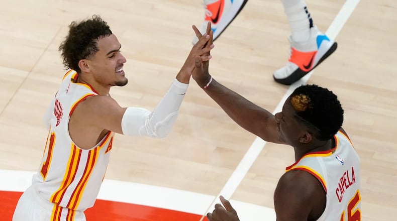 Hawks guard Trae Young (left) and center Clint Capela celebrate during a win earlier in the season. (AP Photo/John Bazemore)