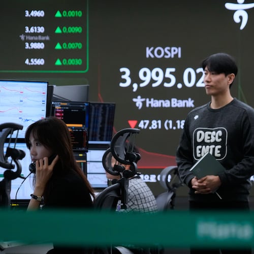 A currency trader talks on the phone near a screen showing the Korea Composite Stock Price Index (KOSPI) and the foreign exchange rate between U.S. dollar and South Korean won, right, at the foreign exchange dealing room of the Hana Bank headquarters in Seoul, South Korea, Tuesday, Oct. 28, 2025. (AP Photo/Ahn Young-joon)