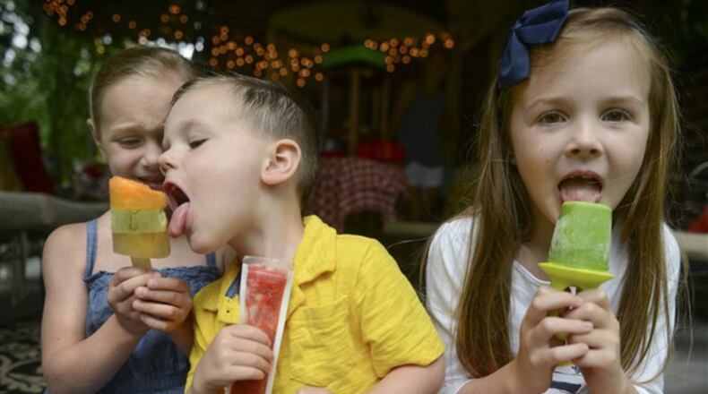 Enjoying homemade popsicles on Thursday, July 6, 2017, are, from left, siblings Mae, Caleb and Autumn Waters. (Steve Mellon/Pittsburgh Post-Gazette/TNS)