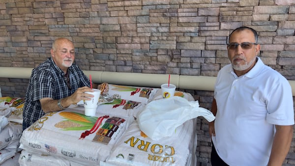 Bassem Zakhary, left, and Jorge Alvarez, of Florida, eat lunch on a pallet of Buc-ee’s Deer Corn at the convenience superstore’s Warner Robins location. (Joe Kovac Jr./AJC)