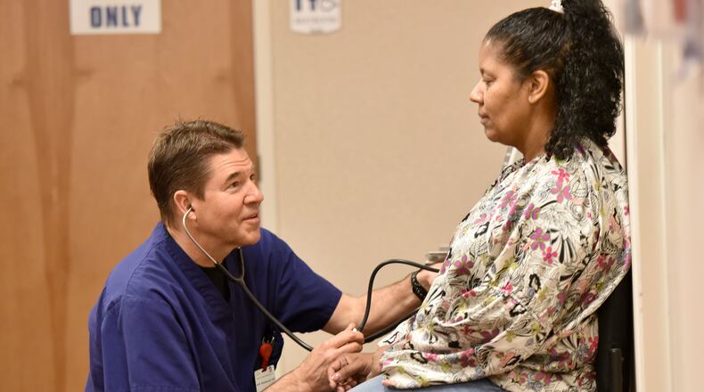 Dr. Jeff Reinhardt examines his patient Carolyn Hollis at The Longstreet Clinic in Gainesville in 2015. HYOSUB SHIN / HSHIN@AJC.COM
