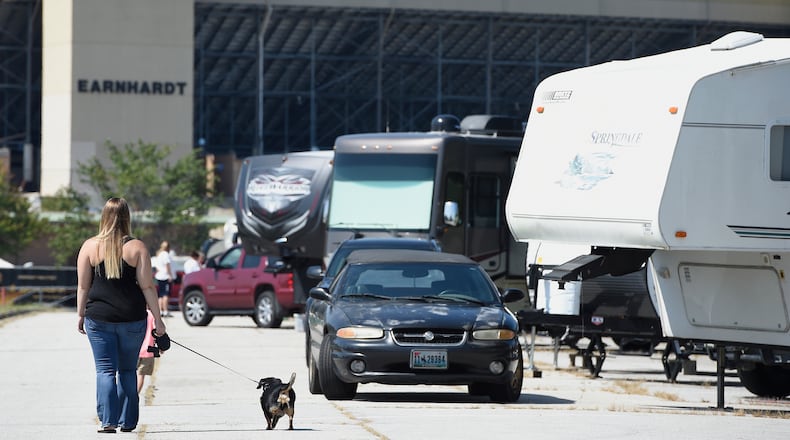 Chelsea Roberson, of Cape Coral, Fla., walks her dog near her parked RV at the Atlanta Motor Speedway, Friday, Sept. 8, 2017, in Hampton, Ga. Over 50 cameras and RV's are sheltering at the speedway from South Ga., South Carolina, and Florida. (AP Photo/Mike Stewart)
