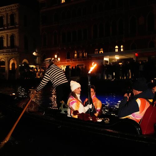 A torchbearer holds an Olympic torch flame on the Grand Canal in Venice, Italy, Thursday, Jan. 22, 2026, and its journey will conclude in Milan on February 6 for the Winter Olympics opening ceremony. (AP Photo/Luca Bruno)