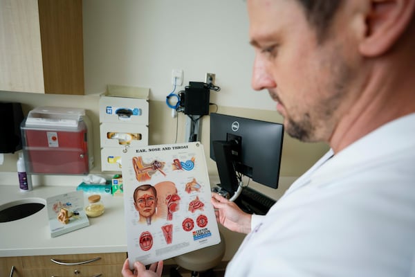 Dr. Timothy Ryan uses a laminated educational sheet to help describe how pollen affects people with allergies. (Miguel Martinez/AJC)