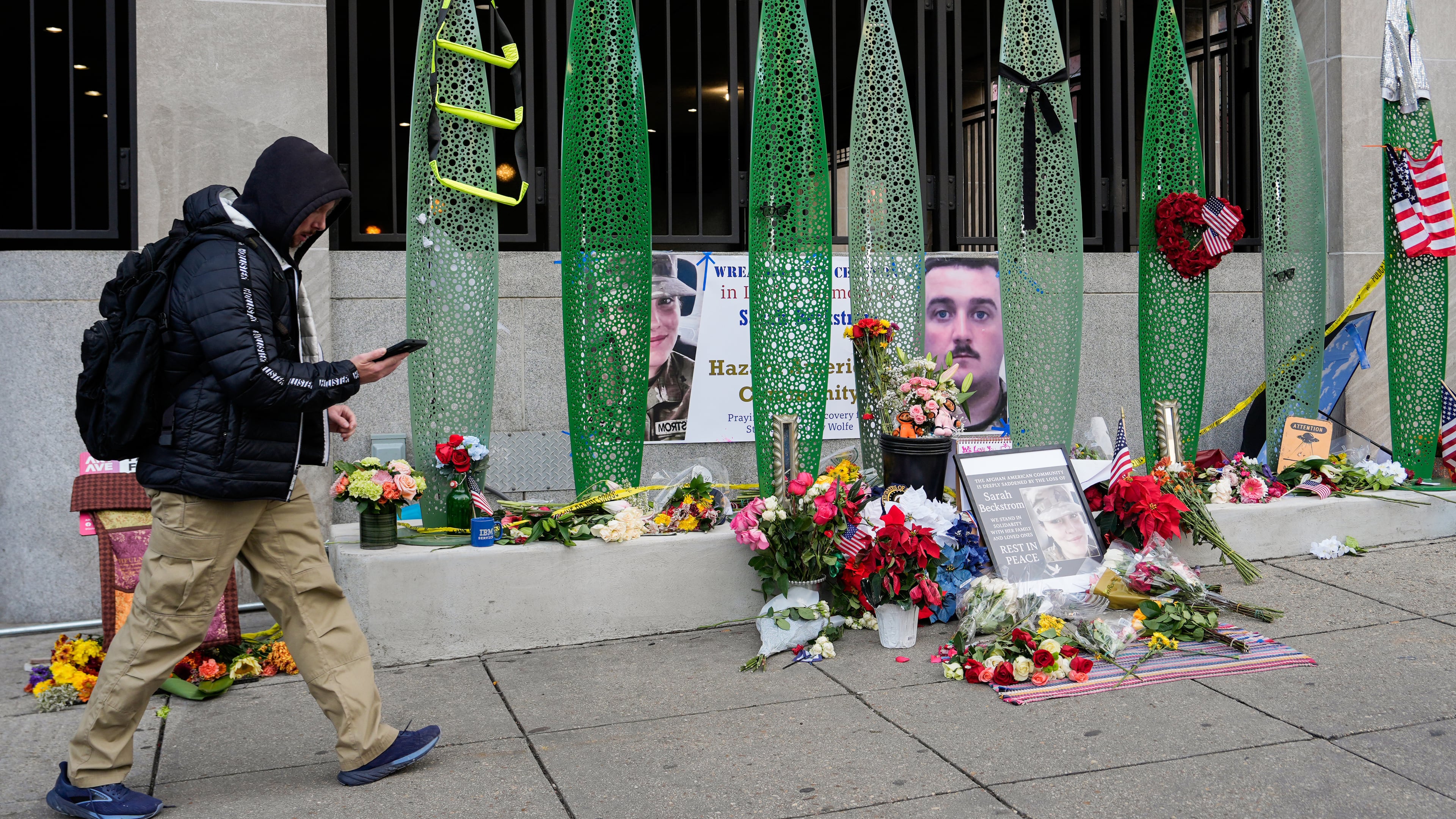 A person walks past a makeshift memorial for U.S. Army Spc. Sarah Beckstrom and U.S. Air Force Staff Sgt. Andrew Wolfe outside of Farragut West Station, near the site where the two National Guard members were shot, Monday, Dec. 1, 2025, in Washington. (AP Photo/Julia Demaree Nikhinson)