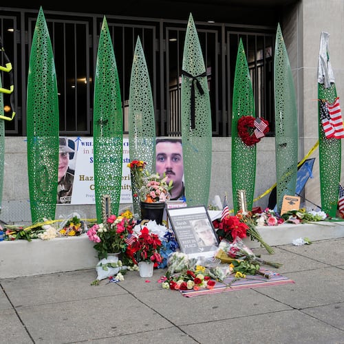 A person walks past a makeshift memorial for U.S. Army Spc. Sarah Beckstrom and U.S. Air Force Staff Sgt. Andrew Wolfe outside of Farragut West Station, near the site where the two National Guard members were shot, Monday, Dec. 1, 2025, in Washington. (AP Photo/Julia Demaree Nikhinson)