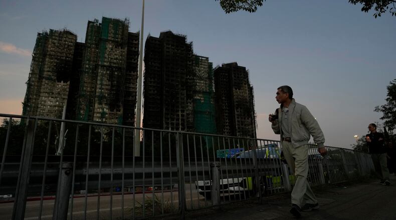 A man walks past the burnt buildings after a deadly fire that started Wednesday at Wang Fuk Court, a residential estate in the Tai Po district of Hong Kong's New Territories, Friday, Nov. 28 2025. (AP Photo/Ng Han Guan)