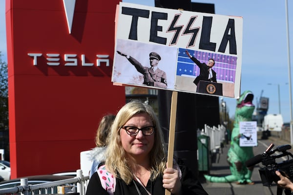 A protester holds a placard as she takes part in the Tesla Takedown Global Day of Action near a Tesla dealership in London, Saturday, March 29, 2025.(AP Photo/Thomas Krych)