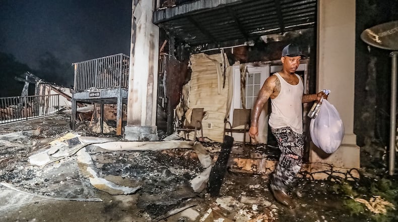 Terrell Samuels carries a bag of clothes from his burned apartment Wednesday morning at the Ashford at Stoneridge Apartments on Flat Shoals Road. It was the only thing he could salvage from his fire-destroyed home.