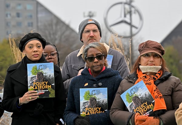Supporters hold pamphlets during an event to launch its policy platform outlining community-driven demands ahead of the 2026 FIFA World Cup on the Steele Bridge near the Mercedes-Benz Stadium, Thursday, December 4, 2025, in Atlanta. (Hyosub Shin / AJC)