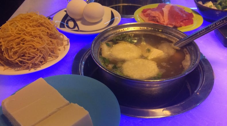 A pot of oxtail broth at I Luv Hot Pot is ready for filling with ingredients plucked from the conveyor belt: tofu, noodles, egg, and sliced beef brisket. CONTRIBUTED BY WENDELL BROCK