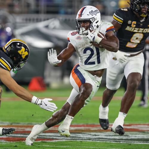 Virginia running back Harrison Waylee (21) shows a stiff-arm to Missouri safety Caleb Flagg, left, during the second quarter of the Gator Bowl NCAA college football game in Jacksonville, Fla., Saturday, Dec. 27, 2025. (AP Photo/Gary McCullough)