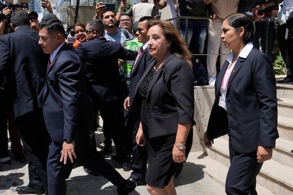 Peruvian President Dina Boluarte, center, is surrounded by security as she leaves the home of the late Peruvian Nobel literature laureate Mario Vargas Llosa, where she gave her condolences to his family the day after his death, in Lima, Peru, Monday, April 14, 2025. (AP Photo/Martin Mejia)