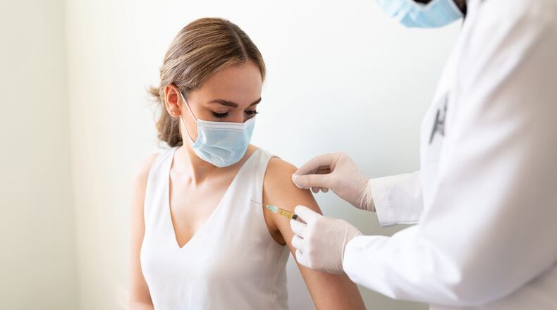 Doctor using a cotton swab with alcohol to clean a woman's arm before applying a vaccine in a doctor's office. (Adobe Image Purchased & Provided Courtesy Good Sam Gwinnett)
