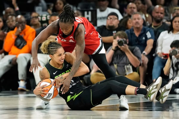 Seattle Storm forward Gabby Williams, left, and Las Vegas Aces guard Jewell Loyd scramble for the ball during the second half of a WNBA basketball game Friday, June 20, 2025, in Las Vegas. (AP Photo/John Locher)