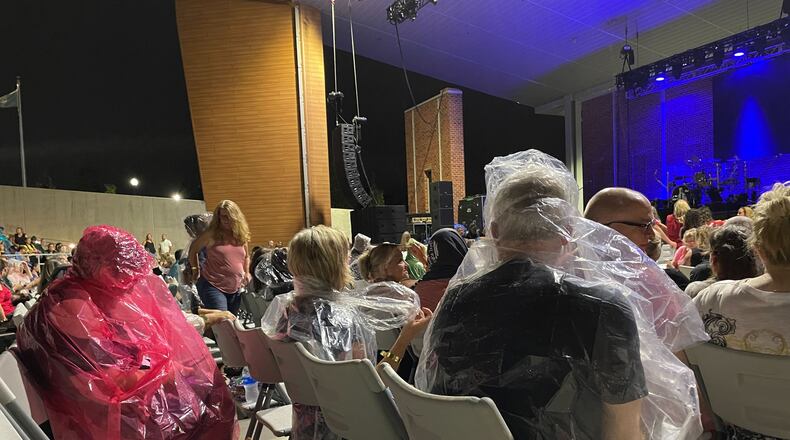 Fans of Rick Springfield and Men at Work wear rain gear as they await an Aug. 6 outdoor concert in Stockbridge. The event was canceled midway through the concert because of lightning and rain. (Photo: Leon Stafford / AJC)