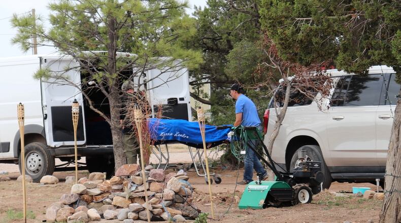 Workers remove a body in Mountainair, N.M., Wednesday, May 20, 2026, after several people died and more than a dozen first responders were exposed to an unknown substance. (AP Photo/Savannah Peters)