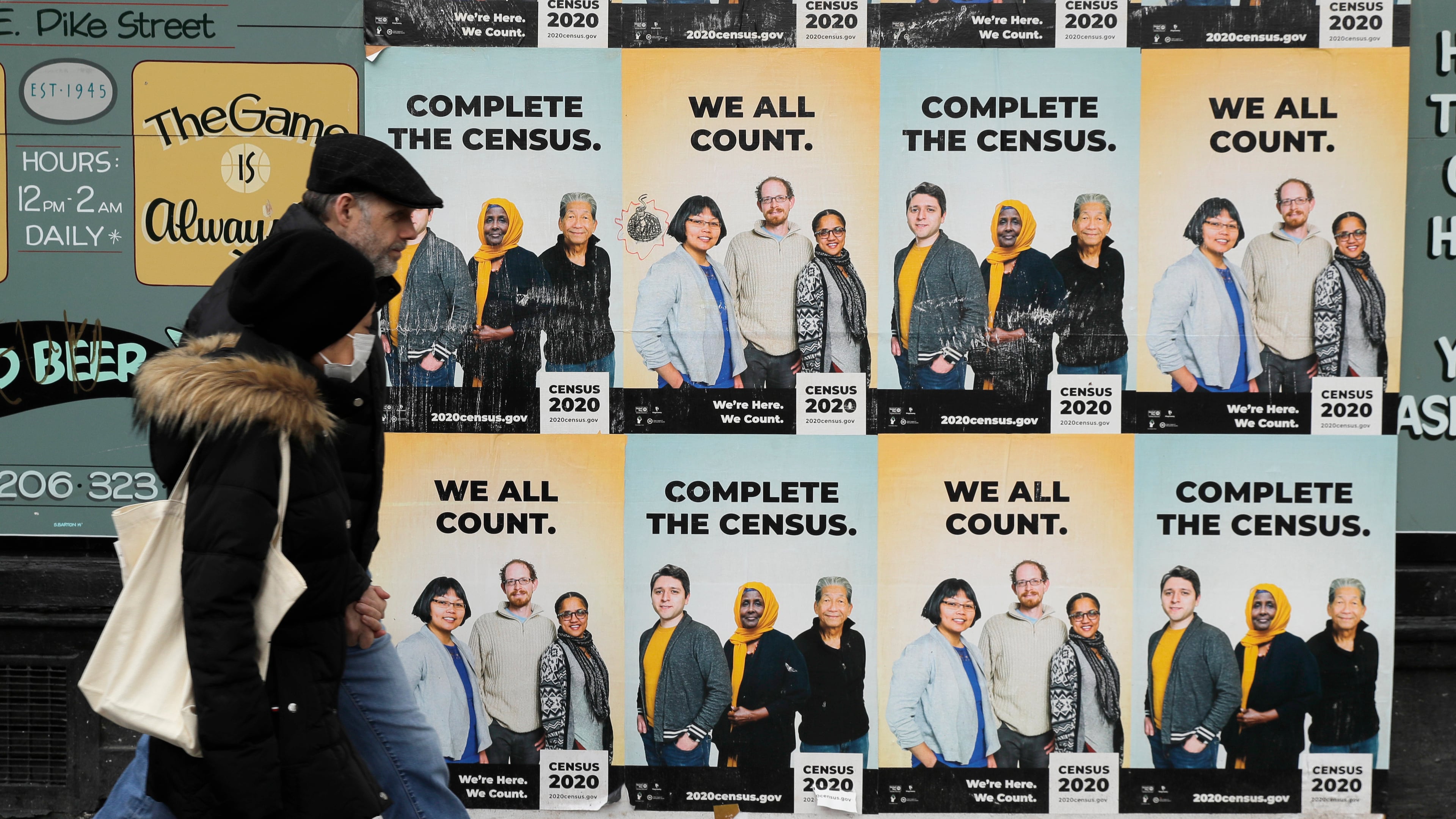 FILE - In this Wednesday, April 1, 2020 file photo,People walk past posters encouraging participation in the 2020 Census in Seattle's Capitol Hill neighborhood. (AP Photo/Ted S. Warren, File)