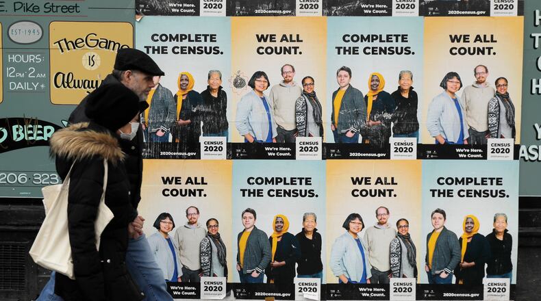 FILE - In this Wednesday, April 1, 2020 file photo,People walk past posters encouraging participation in the 2020 Census in Seattle's Capitol Hill neighborhood. (AP Photo/Ted S. Warren, File)