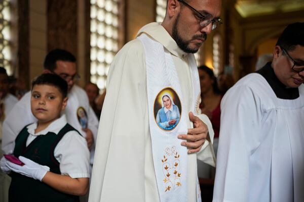 A priest attends a celebratory Mass for Blessed Maria Carmen Rendiles wearing a image of her at Belen's school church where are their remains in Caracas, Venezuela, Monday, March 31, 2025. (AP Photo/Ariana Cubillos)