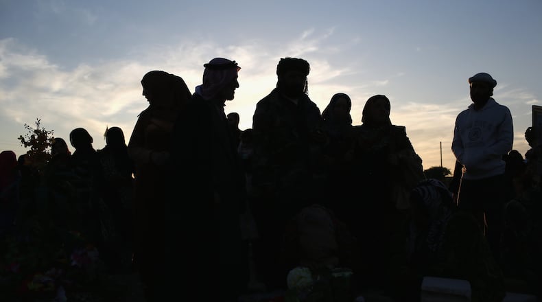 QAMISHLI, SYRIA - NOVEMBER 12: Family members pay their respects in a martyrs' cemetery for soldiers from the People's Protection Units (YPG), killed fighting ISIL on November 12, 2015 in Qamishli, Rojava, Syria. The predominantly Kurdish regions of northern Syria and Iraq have become bastions against the Islamic State, with the help of U.S. airstrikes. In Iraq, Kurdish Peshmerga forces launched an offensive to drive the extremists from Sinjar, which they had captured in 2014, killing and enslaving thousands of minority Yazidis. (Photo by John Moore/Getty Images)