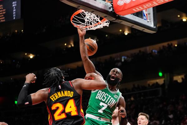 Boston Celtics guard Jaylen Brown (7) scores as Atlanta Hawks forward Bruno Fernando (24) defends during the second half of an NBA basketball game Thursday, March 28, 2024, in Atlanta. (AP Photo/John Bazemore)