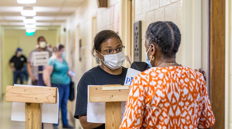 Voters wait in long lines, at times in the rain, at New Beginnings Full Gospel Church as Election Protection volunteer Angela Walker, second from right, talks with the polling location manager Tuesday, June 9, 2020. The lines were taking more than 3.5 hours. This polling location opened at 7 am with only one machine of the four available working and had two of the four working at 4:30 and were not providing provisional ballots. Walker is working on election quality control for the non-profit organization. (Jenni Girtman for The Atlanta Journal-Constitution)