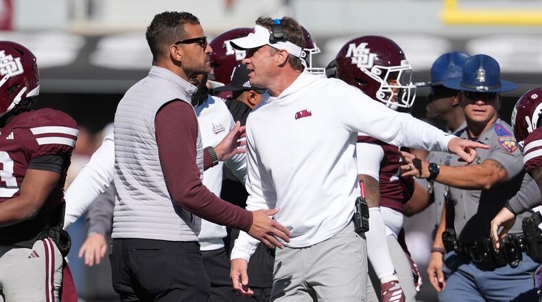 Mississippi head coach Lane Kiffin, right, and Mississippi State director of athletics Zac Selmon, left, confer during a scuffle between the teams in the first half of an NCAA college football game Friday, Nov. 28, 2025, in Starkville, Miss. (AP Photo/Rogelio V. Solis)