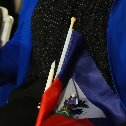 FILE - People hold hands and a Haitian flag during a vigil at the Little Haiti Cultural Complex after a federal judge blocked the Trump administration from ending temporary immigration status, or TPS, for Haitians, Feb. 3, 2026, in North Miami. (AP Photo/Lynne Sladky, File)