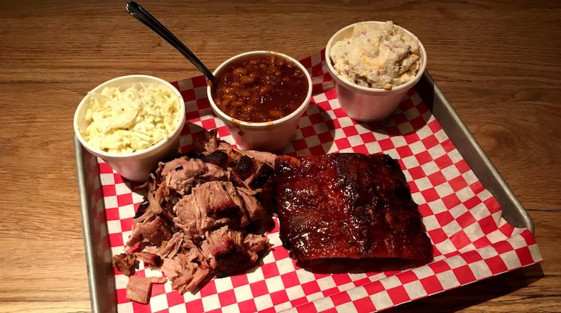 A platter of pulled pork and baby back ribs at King Barbecue is made better with sides of coleslaw, baked beans and potato salad. CONTRIBUTED BY WYATT WILLIAMS